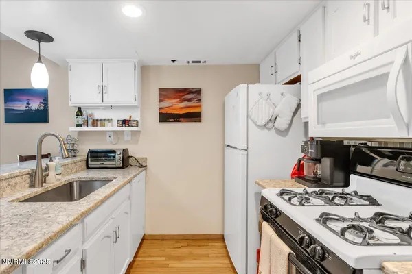 a kitchen with granite countertop a sink a counter space appliances and cabinets