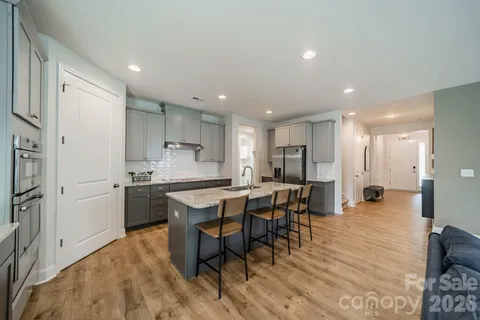 a kitchen with stainless steel appliances kitchen island granite countertop a table chairs sink and cabinets