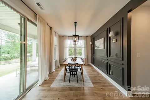 a dining room with wooden floor and large windows