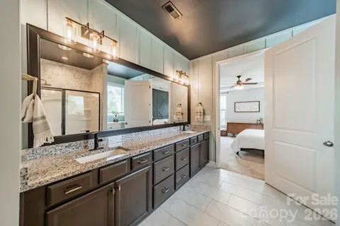 a spacious en suite bathroom with a granite countertop sink and a mirror