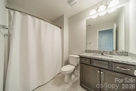 a bathroom with a granite countertop sink toilet and mirror