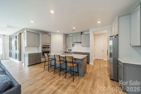 a kitchen with stainless steel appliances a dining table chairs wooden floor and a refrigerator