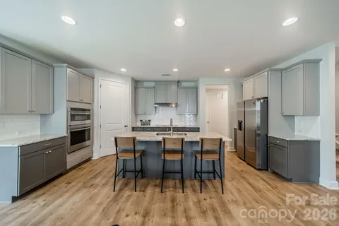 a kitchen with stainless steel appliances a dining table chairs stove refrigerator and cabinets