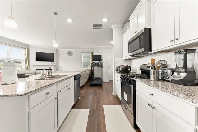 a kitchen with stainless steel appliances granite countertop a sink dishwasher stove top oven and refrigerator