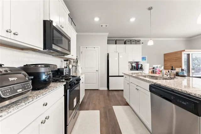 a kitchen with stainless steel appliances granite countertop a sink a stove a refrigerator and cabinets