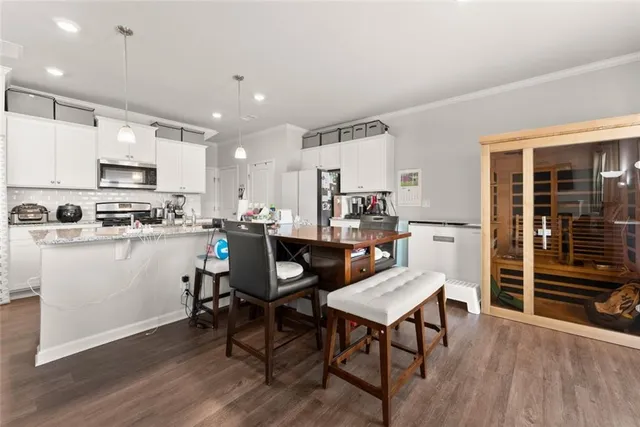 a kitchen with stainless steel appliances a dining table chairs stove refrigerator and cabinets