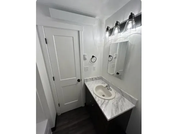 a bathroom with a granite countertop sink a mirror and shower