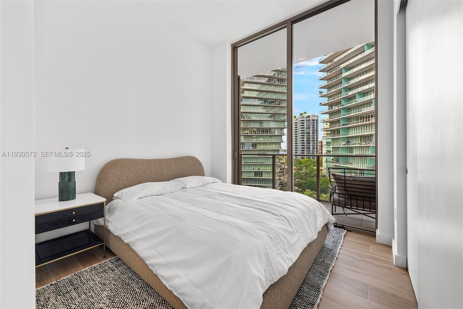 2655 South Bayshore Drive, Unit 909 Miami, FL 33133 - Photo 21 of 26 a bedroom with a bed and wooden floor