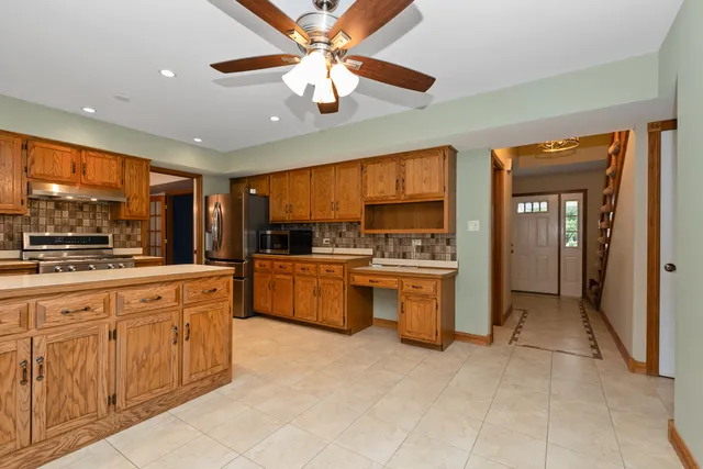 a large kitchen with kitchen island a large counter space a sink stainless steel appliances and cabinets