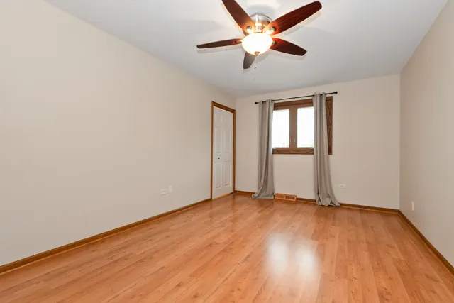 an empty room with wooden floor ceiling fan and windows