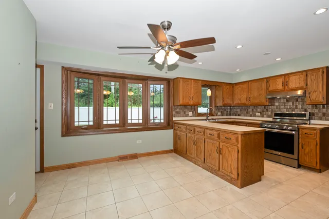 a large kitchen with granite countertop a stove top oven a sink a counter space and a window