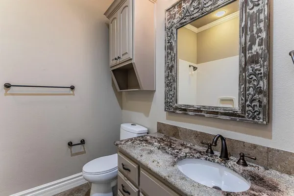 a bathroom with a granite countertop sink a mirror and a toilet