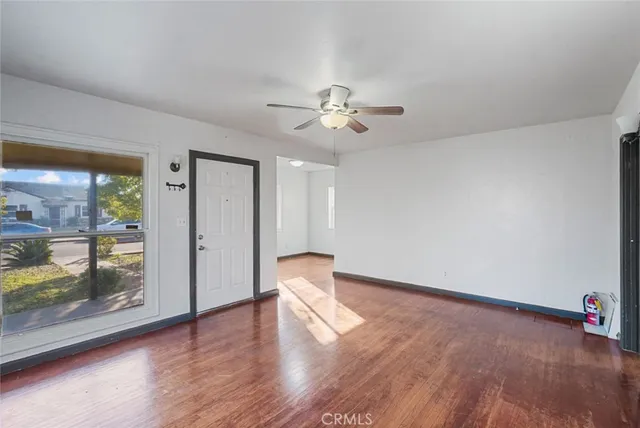 a view of empty room with wooden floor and fan