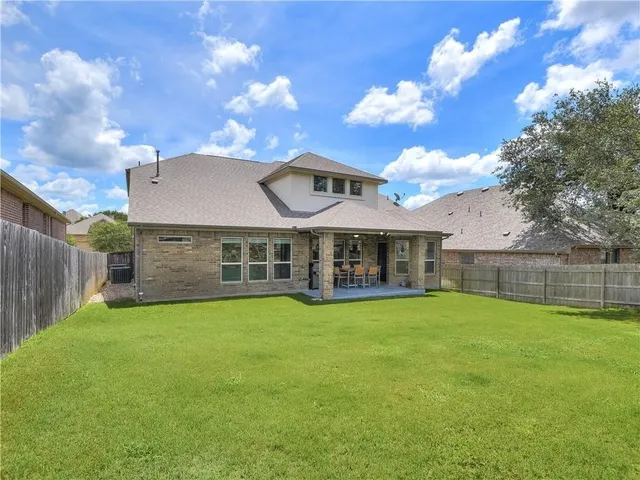 a view of a house with a yard and a large tree