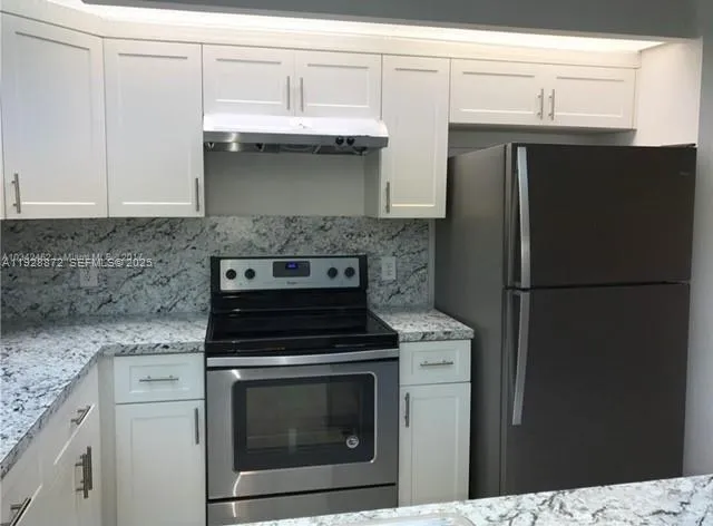 a kitchen with stainless steel appliances granite countertop a stove a refrigerator and a sink