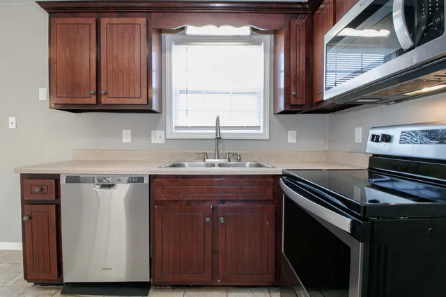 a kitchen with stainless steel appliances granite countertop a sink a stove and a microwave