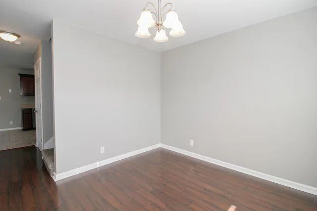 a view of an empty room with wooden floor and a ceiling fan
