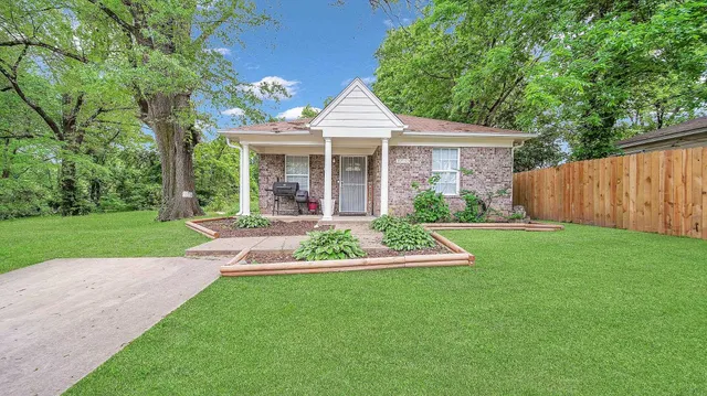 a front view of a house with a yard and green space