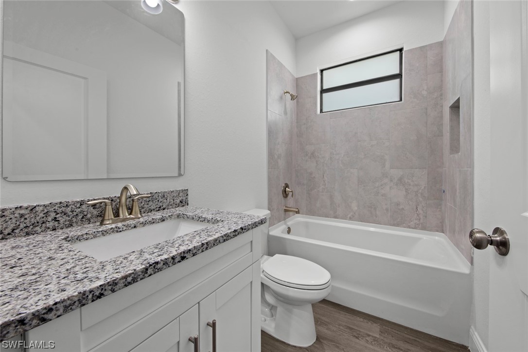 367 Ranier Avenue Lehigh Acres, FL 33974 - Photo 17 of 24 a bathroom with a granite countertop sink a toilet and bathtub
