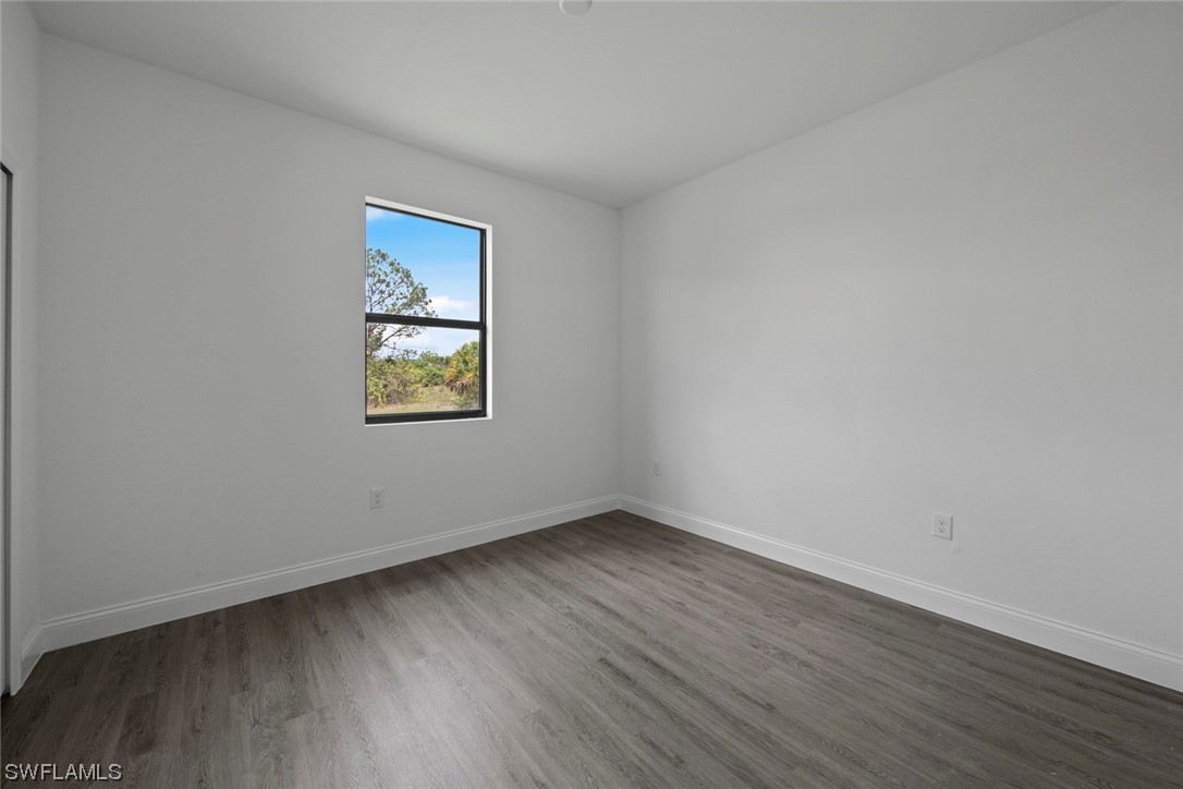 367 Ranier Avenue Lehigh Acres, FL 33974 - Photo 18 of 24 a view of an empty room with wooden floor and a window