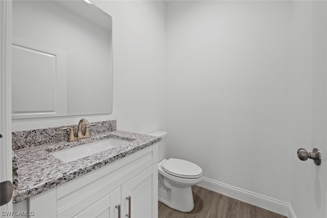 367 Ranier Avenue Lehigh Acres, FL 33974 - Photo 19 of 24 a bathroom with a granite countertop sink a toilet and mirror
