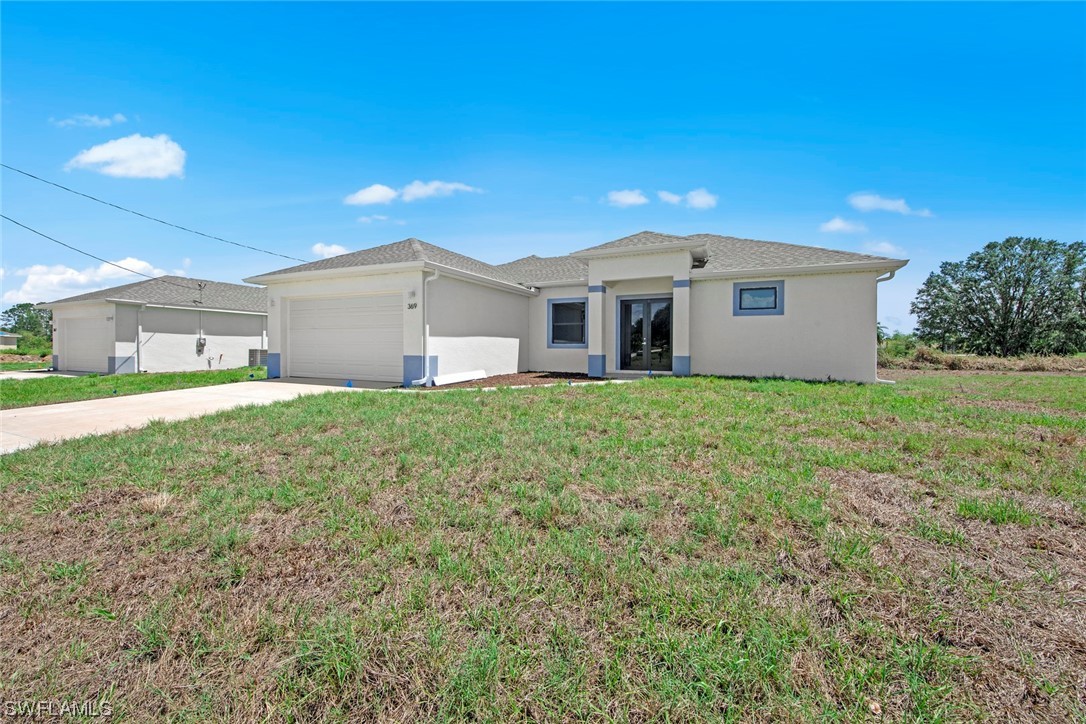 367 Ranier Avenue Lehigh Acres, FL 33974 - Photo 2 of 24 a front view of house with yard and green space