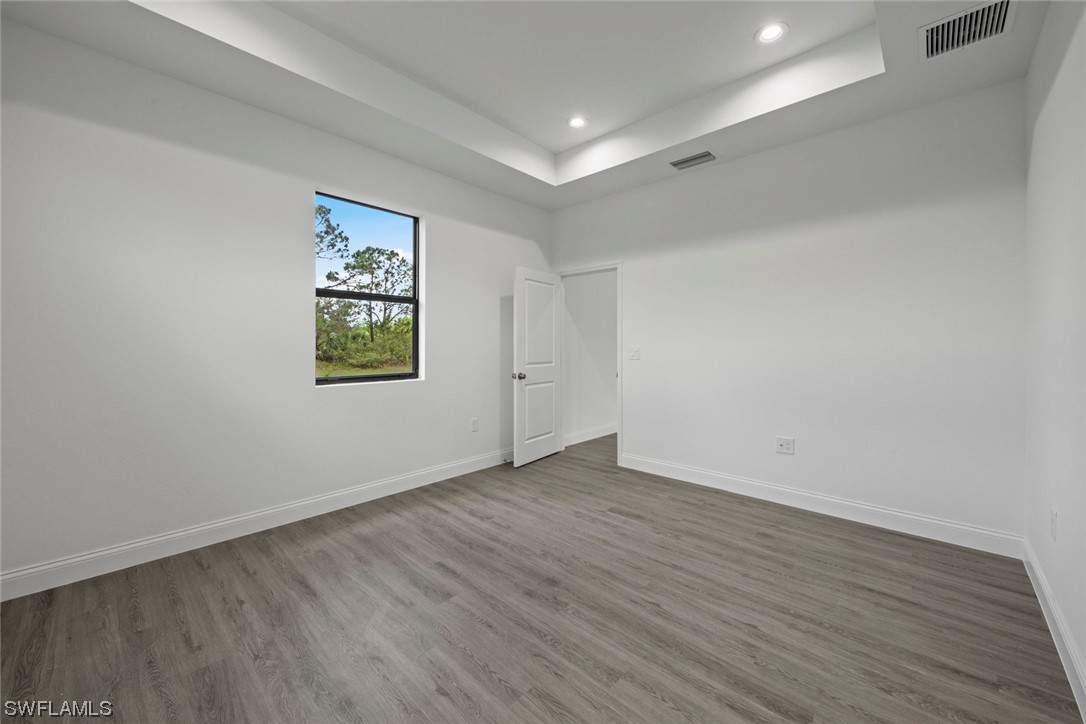 367 Ranier Avenue Lehigh Acres, FL 33974 - Photo 22 of 24 a view of an empty room with wooden floor and a window