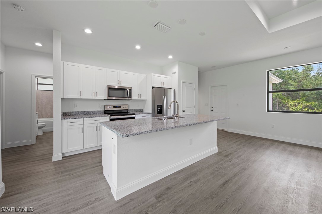 367 Ranier Avenue Lehigh Acres, FL 33974 - Photo 4 of 24 a kitchen with stainless steel appliances granite countertop a stove a sink and a microwave