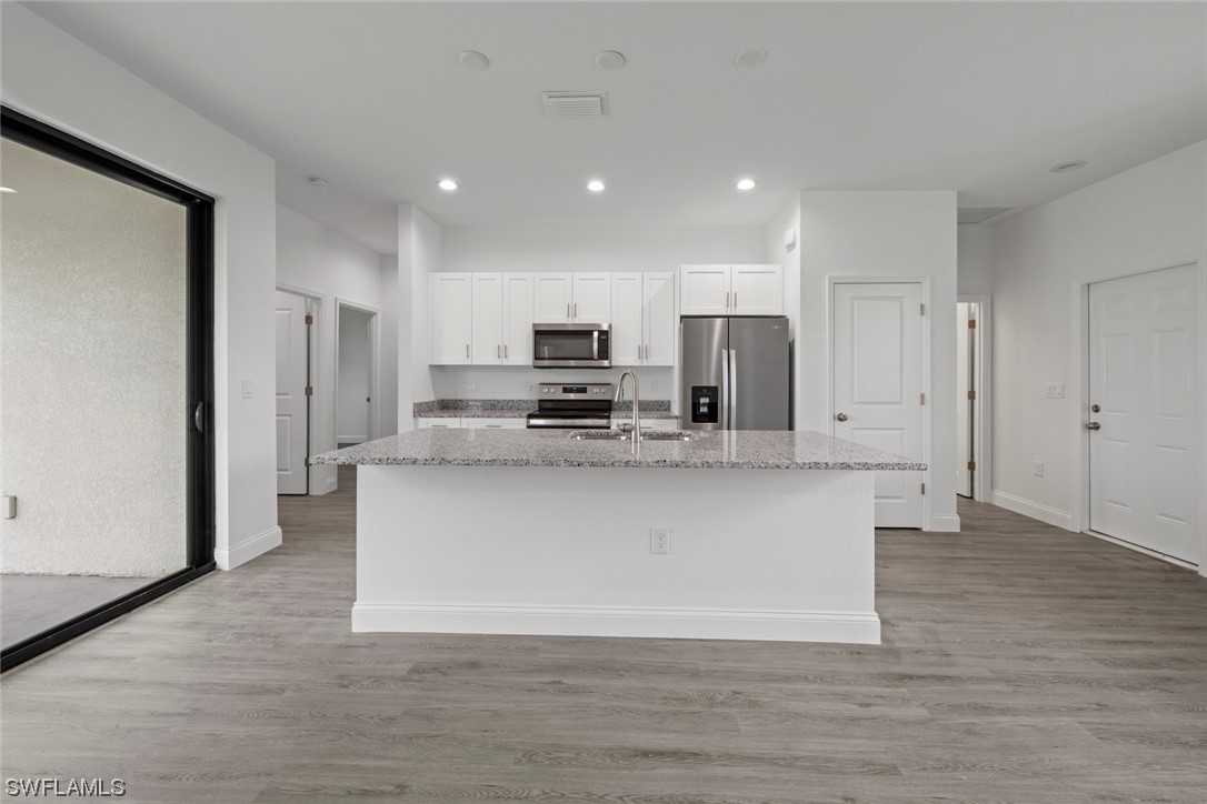 367 Ranier Avenue Lehigh Acres, FL 33974 - Photo 5 of 24 a view of kitchen with stainless steel appliances granite countertop a stove a refrigerator a sink and a oven with wooden floor