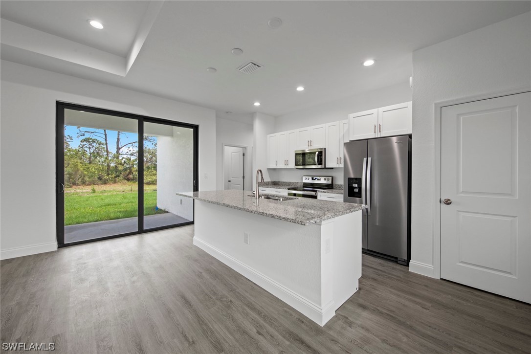 367 Ranier Avenue Lehigh Acres, FL 33974 - Photo 6 of 24 a open kitchen with stainless steel appliances granite countertop a refrigerator a stove a microwave and with wooden floor