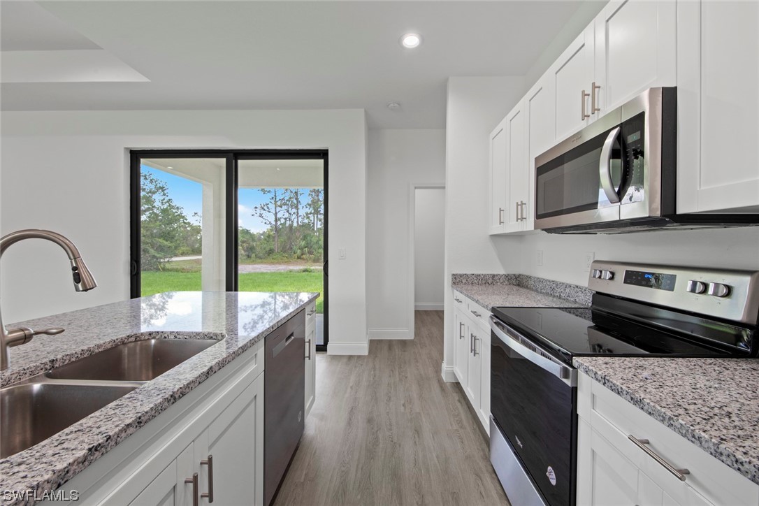 367 Ranier Avenue Lehigh Acres, FL 33974 - Photo 8 of 24 a kitchen with stainless steel appliances granite countertop a sink a stove a microwave and wooden cabinets