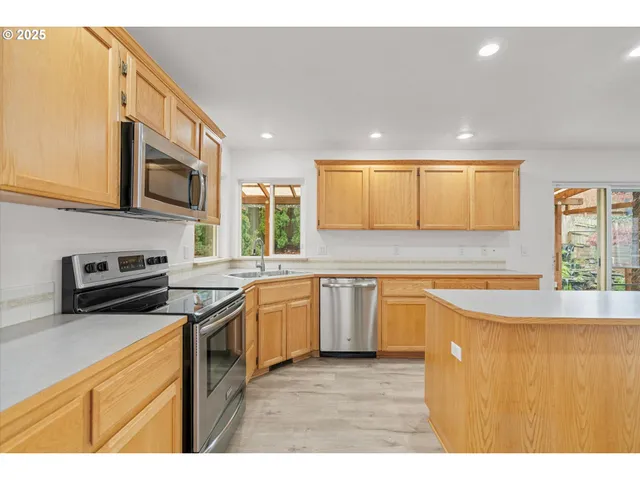 a kitchen with stainless steel appliances granite countertop wooden cabinets a stove a sink a microwave and a refrigerator