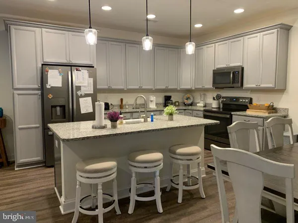 a kitchen with a dining table chairs refrigerator and microwave