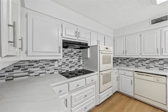 a kitchen with granite countertop white cabinets and white appliances