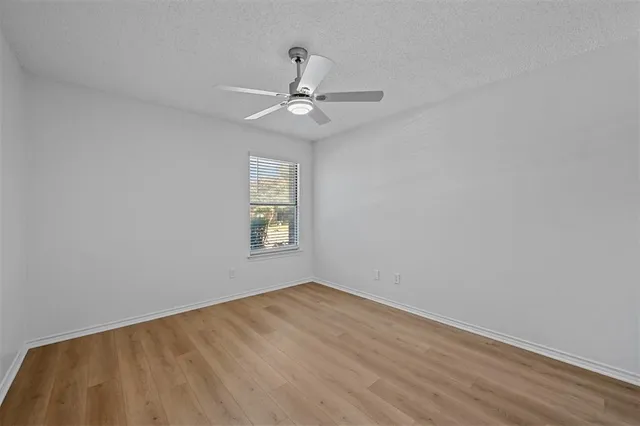 an empty room with a window and ceiling fan