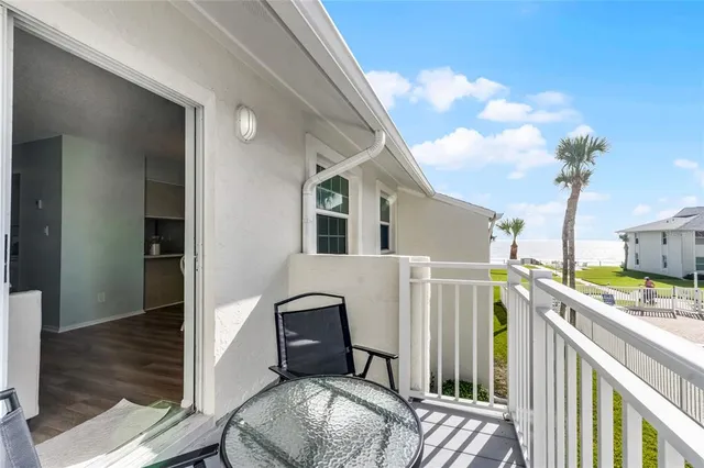 a view of a patio with dining table and chairs with plants and palm trees