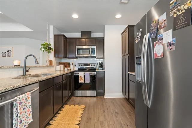a kitchen with stainless steel appliances granite countertop a refrigerator and a stove top oven