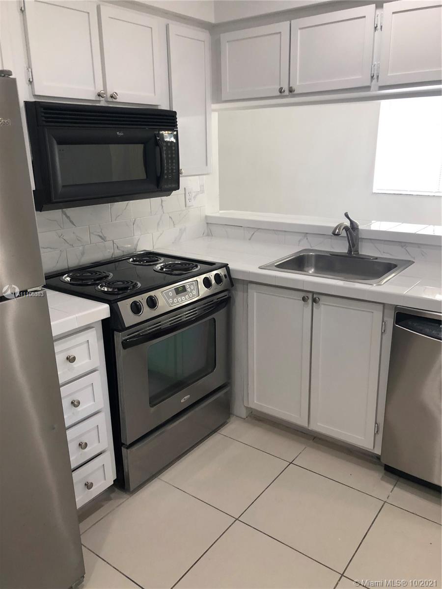9103 Southwest 138th Place, Unit 9103 Miami, FL 33186 - Photo 5 of 30 a kitchen with granite countertop a stove top oven microwave and cabinets