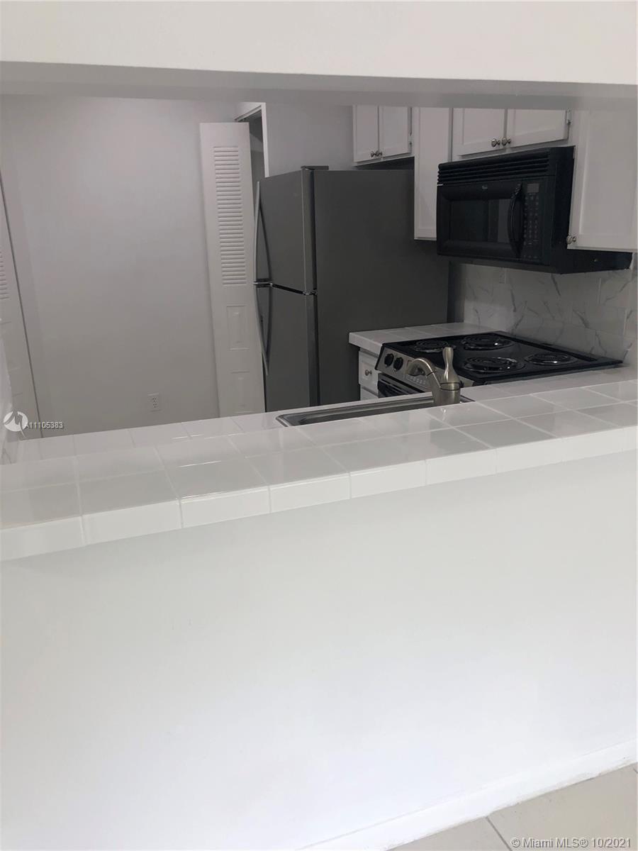 9103 Southwest 138th Place, Unit 9103 Miami, FL 33186 - Photo 6 of 30 a kitchen with a refrigerator and a stove