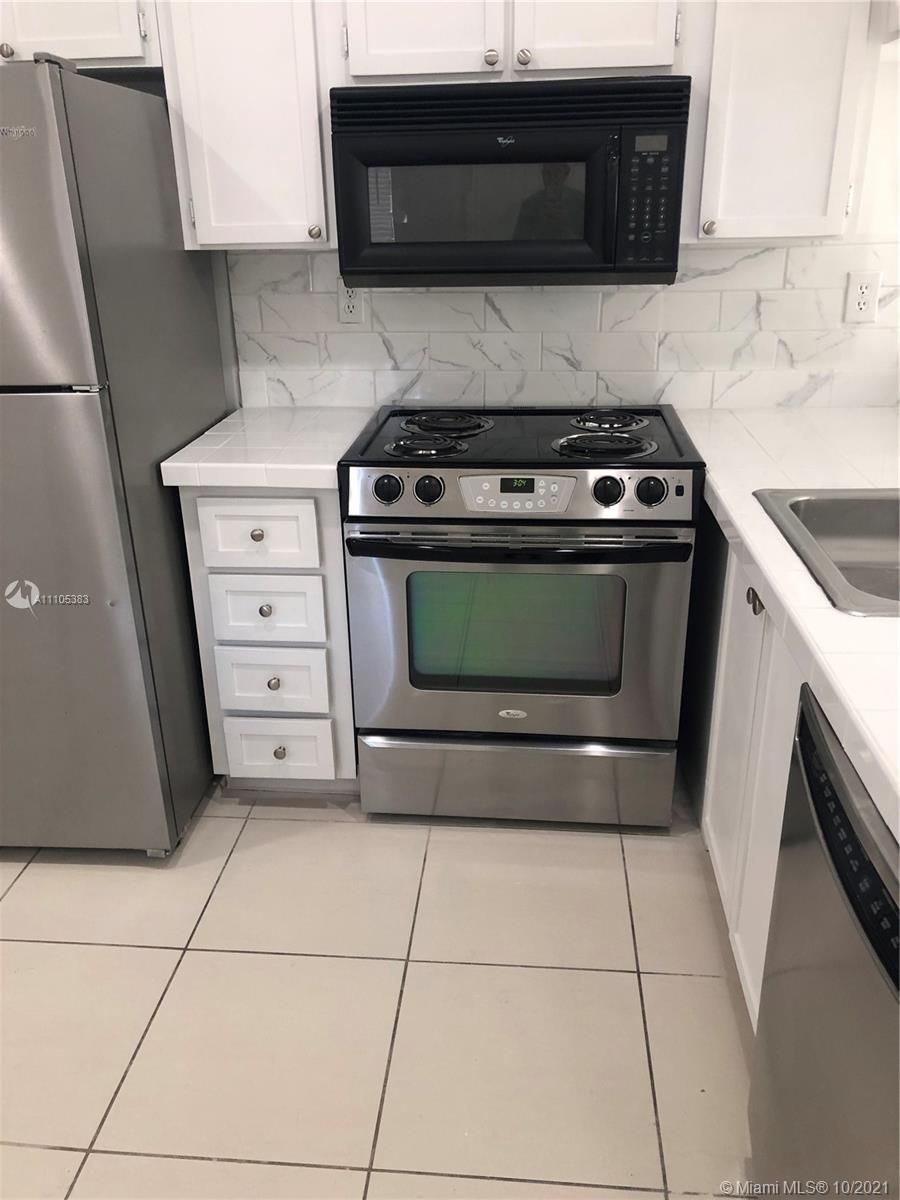 9103 Southwest 138th Place, Unit 9103 Miami, FL 33186 - Photo 8 of 30 a kitchen with a stove and a microwave