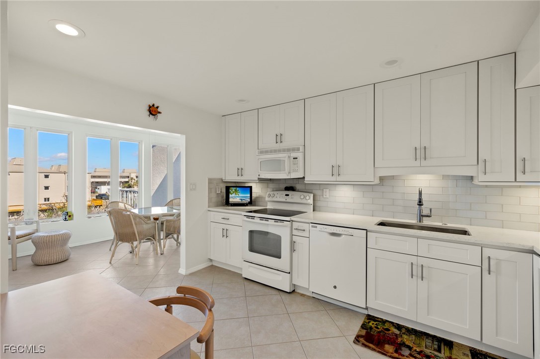 200 Periwinkle Way, Unit 315 Sanibel, FL 33957 - Photo 13 of 33 a kitchen with white cabinets and white appliances
