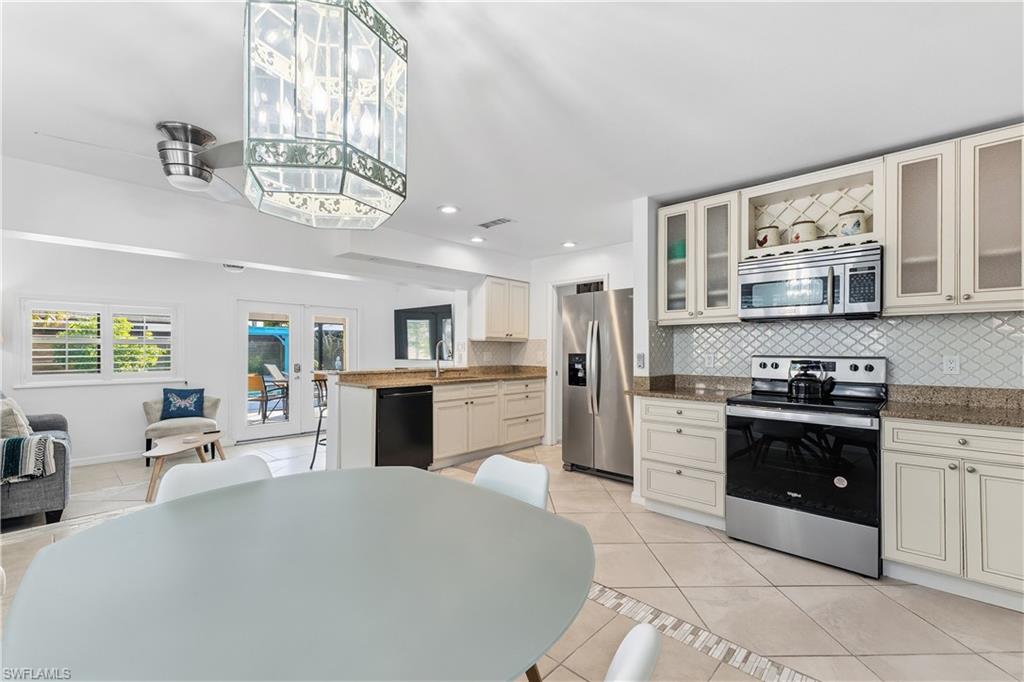 604 110th Avenue North Naples, FL 34108 - Photo 40 of 41 a large kitchen with stainless steel appliances granite countertop a stove oven a sink dishwasher a dining table and chairs with wooden floor