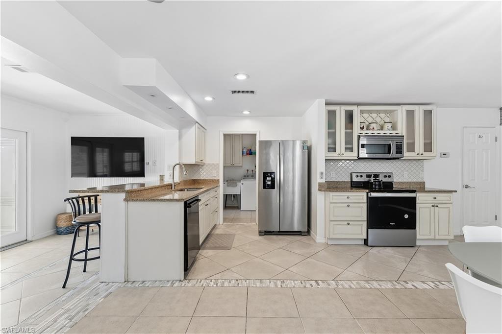 604 110th Avenue North Naples, FL 34108 - Photo 7 of 41 a large kitchen with stainless steel appliances kitchen island granite countertop a refrigerator and a stove top oven