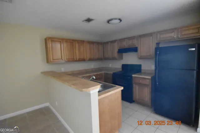 a utility room with a sink a cabinetry and a refrigerator