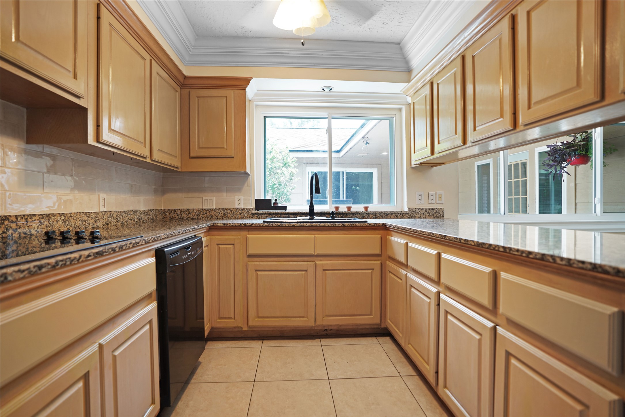 17119 Mellow Ridge Drive Spring, TX 77379 - Photo 9 of 32 This kitchen features ample wooden cabinetry, granite countertops, and a large window providing natural light. It includes modern appliances and a neutral tile floor, creating a functional and inviting space.