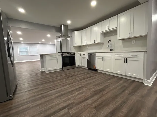 a large kitchen with granite countertop a large counter top a sink stainless steel appliances and cabinets