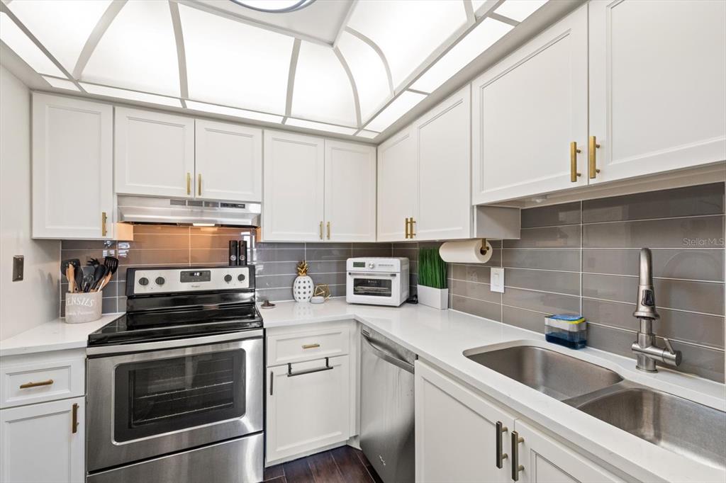 255 Dolphin Point, Unit 508 Clearwater Beach, FL 33767 - Photo 20 of 40 a kitchen with stainless steel appliances a stove a sink and cabinets