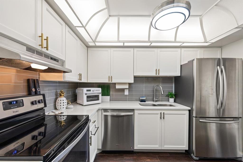 255 Dolphin Point, Unit 508 Clearwater Beach, FL 33767 - Photo 21 of 40 a kitchen with stainless steel appliances a refrigerator a stove and white cabinets