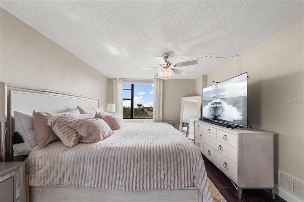 255 Dolphin Point, Unit 508 Clearwater Beach, FL 33767 - Photo 28 of 40 a bedroom with a flat screen tv on dresser and a chandelier