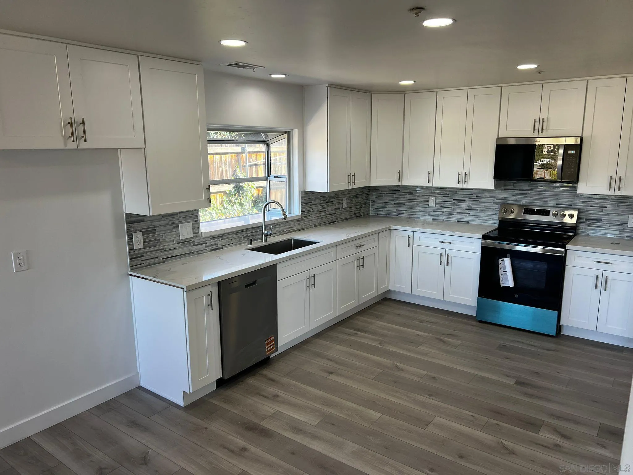 a kitchen with stainless steel appliances granite countertop a stove a sink and white cabinets